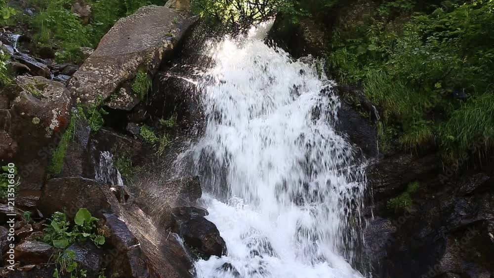 waterfall in the mountains summer park, the rays of the sun make their way through the trees waterfall in the mountains summer park, the rays of the sun make their way through the trees