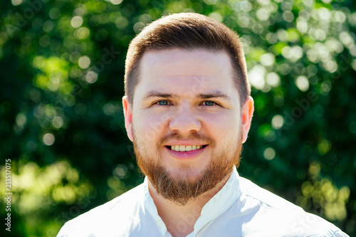 portrait of a bearded man in a white shirt. businessman in the park © yurakrasil