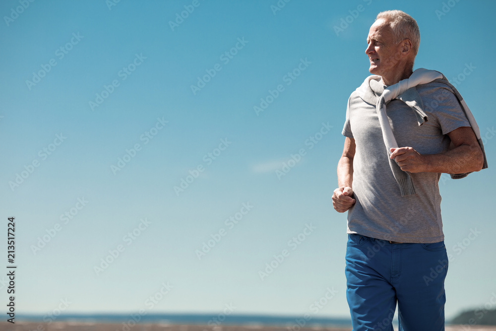 Senior active man running outdoors on sunny summer day on background of blue sky Senior active man running outdoors on sunny summer day on background of blue sky