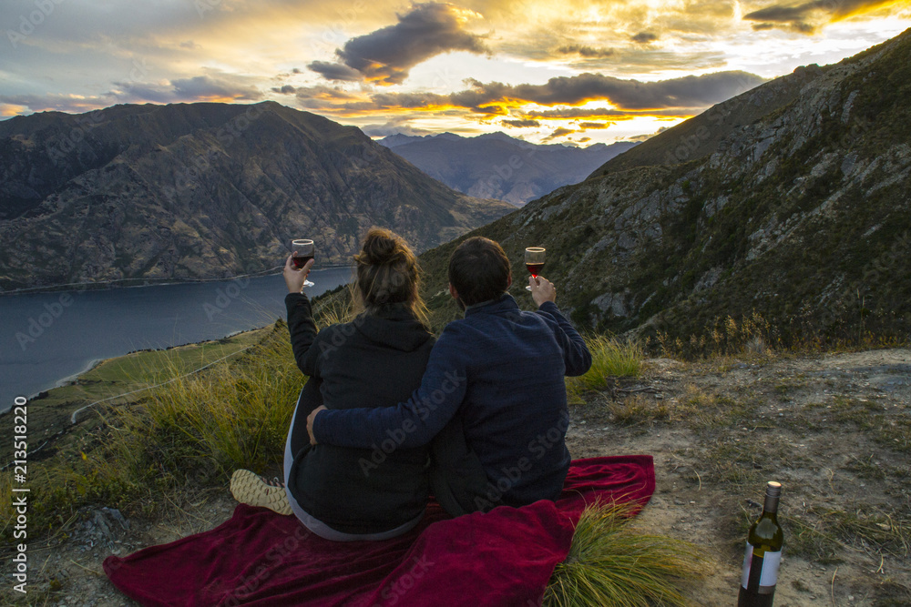 New zealand, Wanaka lake travel vacation. Happy couple/friends happy on the mountain top hands up with wine glasses, enjoying mountain, lake landscape outdoor view. Freedom, happiness lifestyle