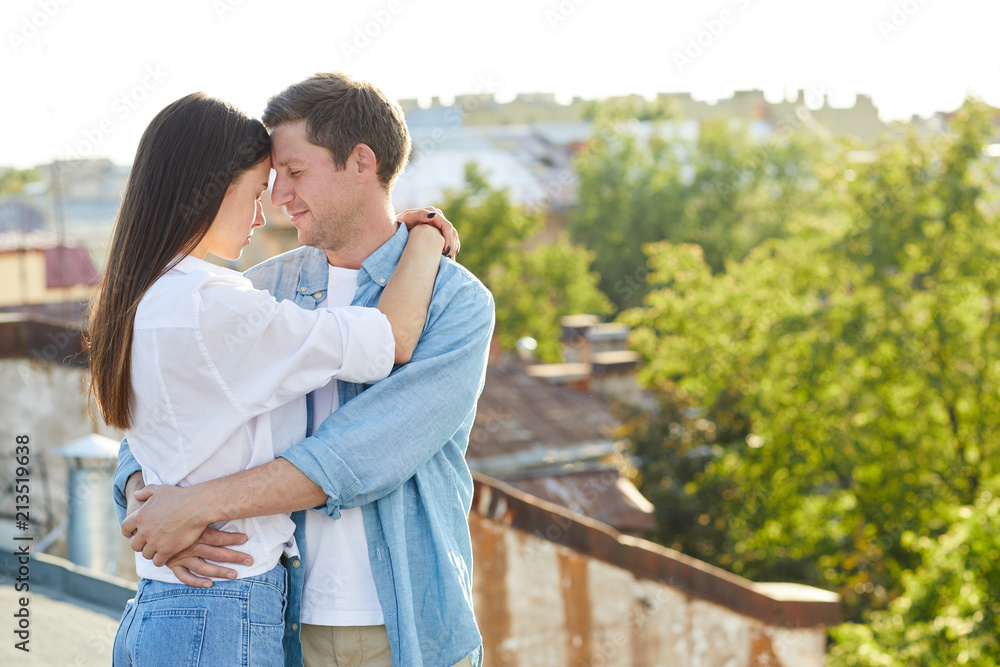 Young amorous couple standing in embrace while enjoying closeness outdoors Young amorous couple standing in embrace while enjoying closeness outdoors