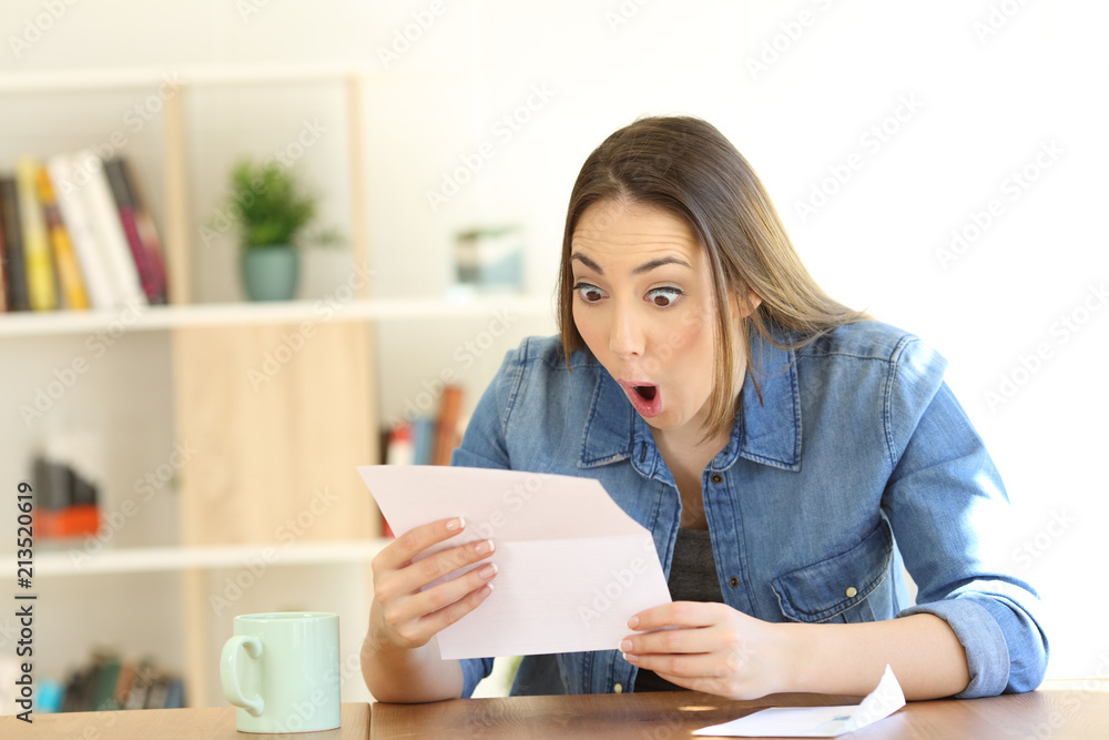 Amazed woman reading surprising news in a letter Amazed woman reading surprising news in a letter