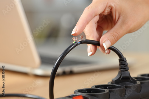 Hand holding a dangerous damaged electrical cord photo