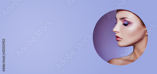 Woman in a round hole circle in purple background, Beauty makeup cosmetics nature fashion, copy space advertising. Professional makeup perfect skin and shiny lipstick. Advertising banner, book cover