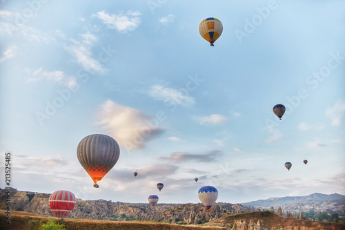 Large number of balloons fly in morning in the sky in rays of the dawn sun. Balloons balloons in the sky in the clouds above the mountains. Main attraction of Cappadocia, Turkey. Fabulous view