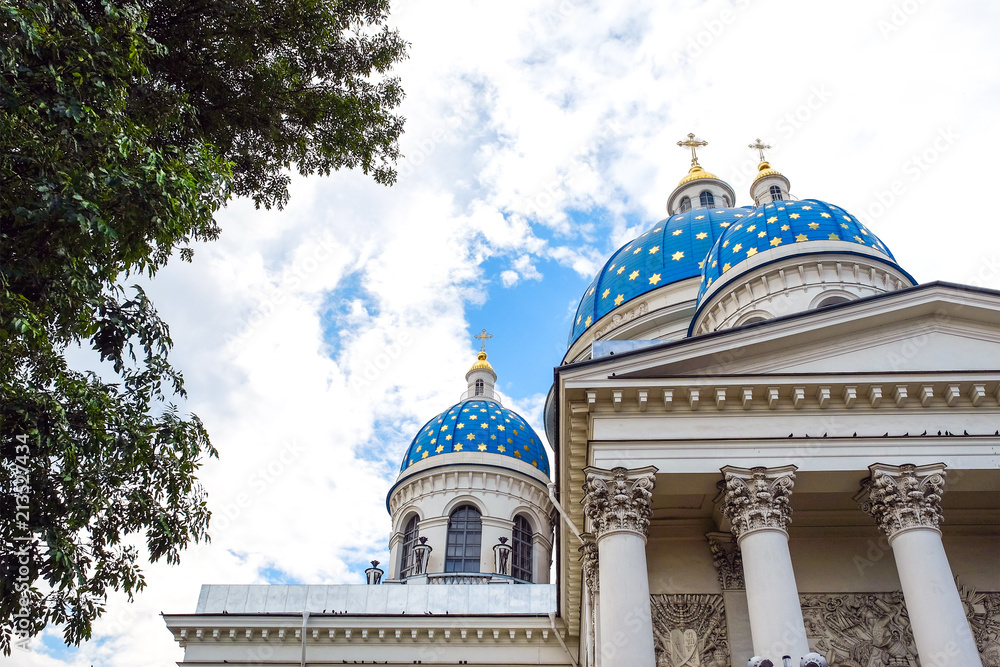 Obraz premium Construction of white brick with dark room. Traffic lights on the sidewalk. Blue Church domes with crosses. Against the blue sky