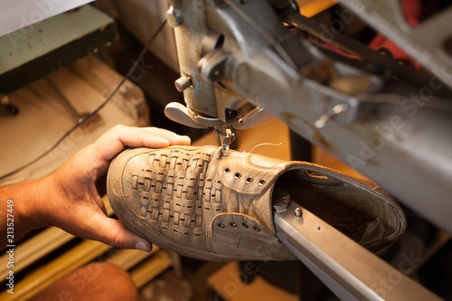 Professional shoemaker heeling footwear on machine in workshop. Classic men's elegance, stitched shoes at the cobbler. adult man working in a shoe factory, sewing the soles of the shoes manually. photo