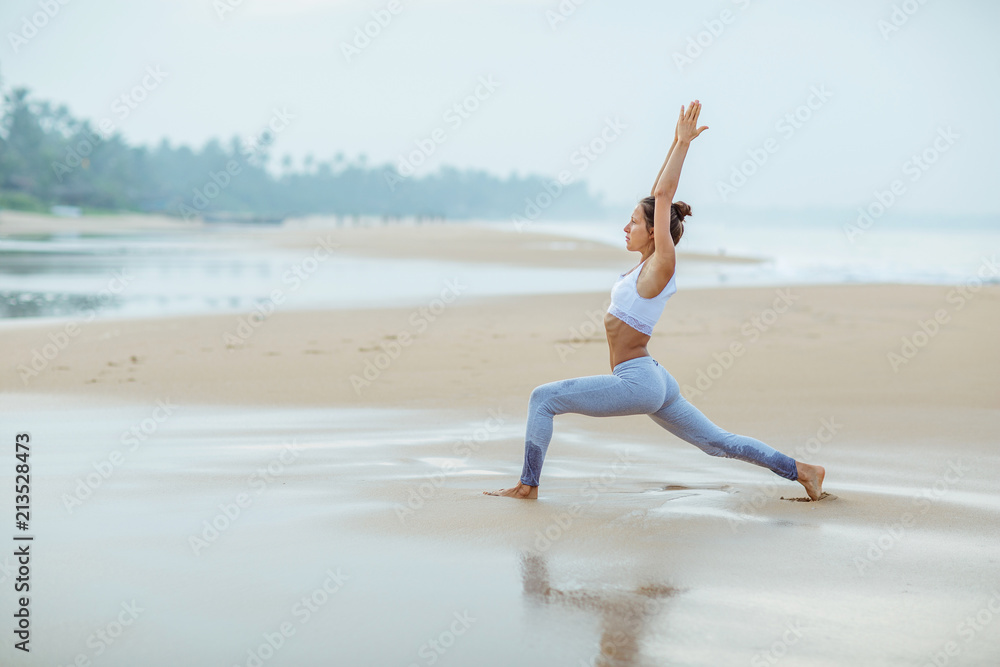 Caucasian woman practicing yoga at seashore of tropic ocean Caucasian woman practicing yoga at seashore of tropic ocean