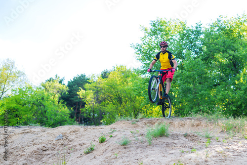 The concept of an active lifestyle, the enduro cyclist descending from the top on a mountain bike, a bright summer photo.