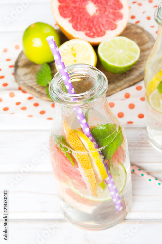 Infused flavored water with fresh fruits on white wooden background.Refreshing summer homemade detox water