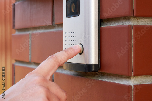 Slika na platnu The female hand presses a button doorbell with intercom