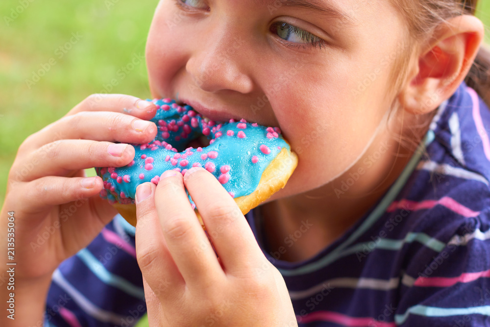 Little girl is eating colored donuts. Little girl is eating colored donuts.