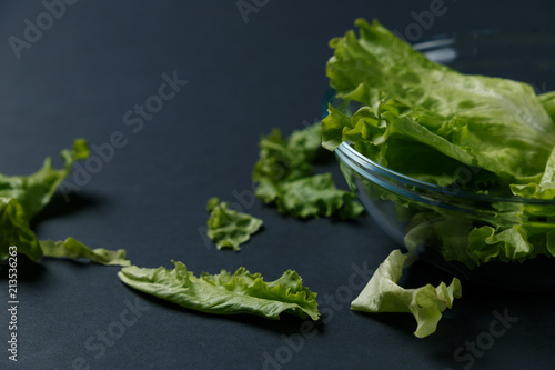 fresh salad leaves in bowl on dark background. Top view