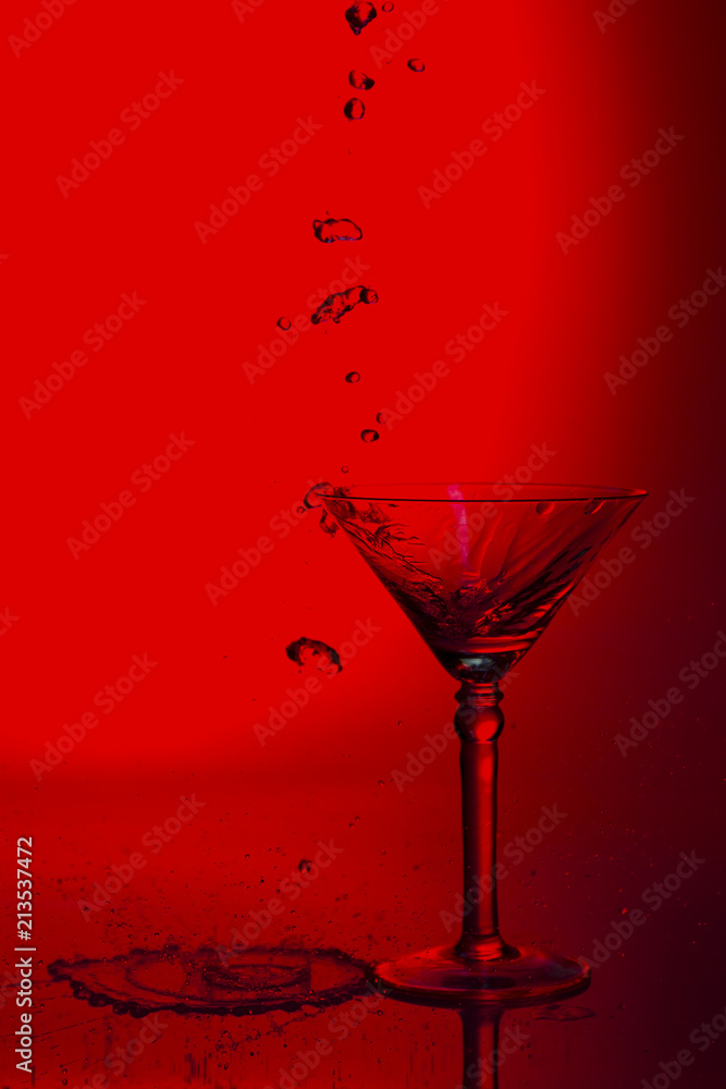 Martini glass high key photo in studio with red tint and water plash Martini glass high key photo in studio with red tint and water plash