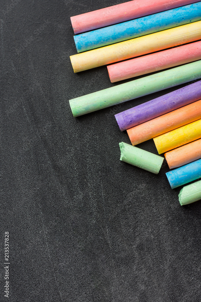 Row Pile of Multicolored Chalks Crayons on Dark Scratched Blackboard. Back to School Business Creativity Graphic Design Crafts Kids Concept. Poster Banner with Copy Space. Top View Row Pile of Multicolored Chalks Crayons on Dark Scratched Blackboard. Back to School Business Creativity Graphic Design Crafts Kids Concept. Poster Banner with Copy Space. Top View