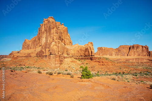 The deep red slickrock formations found along the roadside in Arches National Park are striking against an electric blue sky