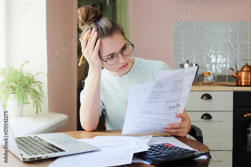 Fotografie Indoor shot of young European Caucasian girl looking at financia