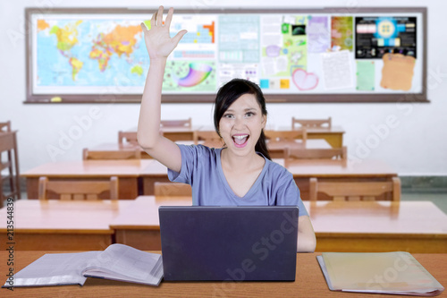 Caucasian student lifts her arm to answer question