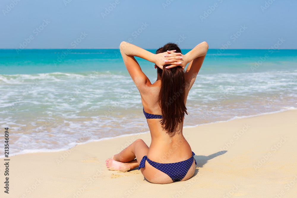 Sexy back of beautiful unrecognizable woman relaxing and sunbathing in  bikini on sea background and palm. Sexy buttocks. Jumeirah beach in Dubai,  UAE famous tourist destination Stock Photo | Adobe Stock