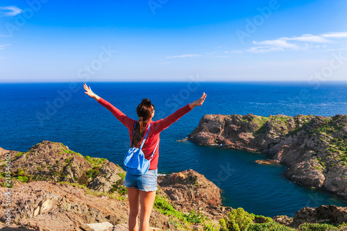 Obraz na płótnie Tourist woman with backpack on Cap de Creus, natural park. Eastern point of Spain, Girona province, Catalonia. Famous tourist destination in Costa Brava. Sunny summer day with blue sky and clouds w salonie