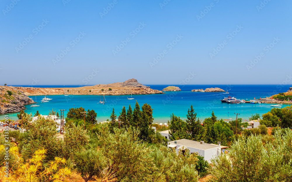 Sea skyview landscape photo Lindos bay and castle on Rhodes island, Dodecanese, Greece. Panorama with ancient castle and clear blue water. Famous tourist destination in South Europe