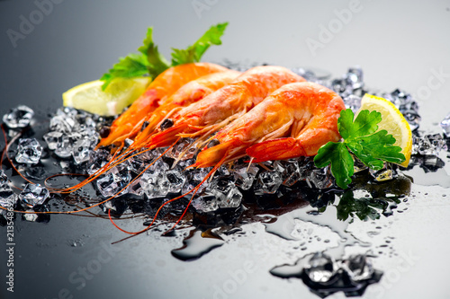 Shrimps. Fresh prawns on a black background. Seafood on crashed ice with herbs. Healthy food, cooking