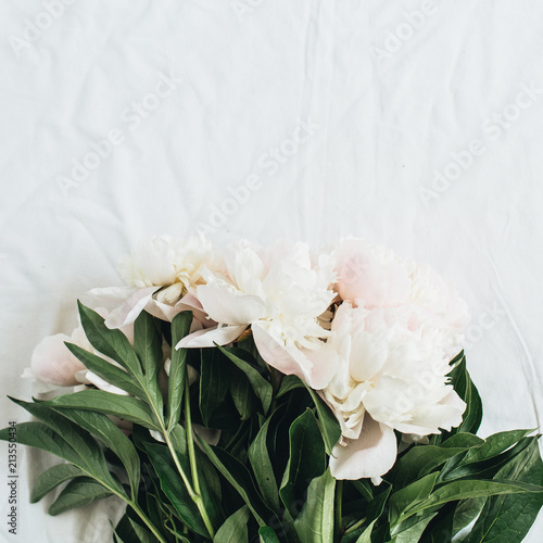 Flat lay, top view of white peonies flower bouquet on white blanket background. © Floral Deco