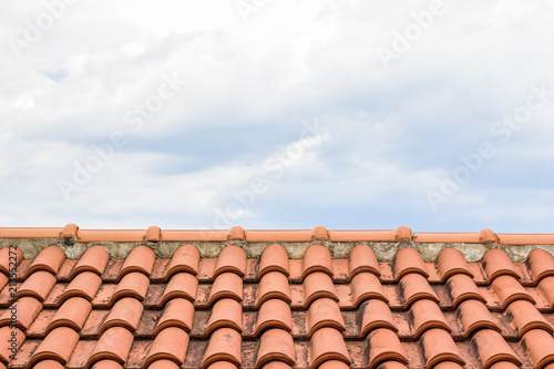 shingles red house roof foreground texture and gray cloudy sky background concept with empty space for copy or text