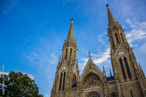 gothic church facade from below on blue blurred sky background in summer colorful bright day time