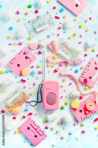 Cassette tapes and retro radio player in a pastel colour flat lay with candies, bonbons, marmalade and bubble gum. Sweet music concept with copy space. Vanilla palette