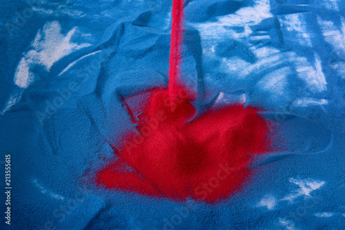 фотографія red sand pouring to the table with blue sand