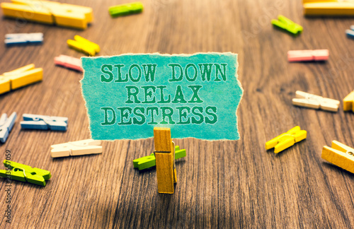 Word writing text Slow Down Relax Destress. Business concept for calming bring happiness and put you in good mood Clothespin holding turquoise paper note several clothespins wooden floor.