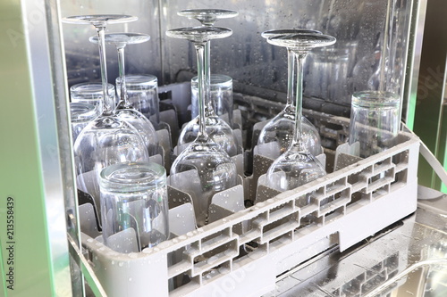 Open dishwasher with clean glass, cups, plates and dishes, selective focus