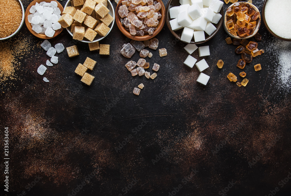 Set of different white and brown sugar in assortment, dark background, top view Set of different white and brown sugar in assortment, dark background, top view