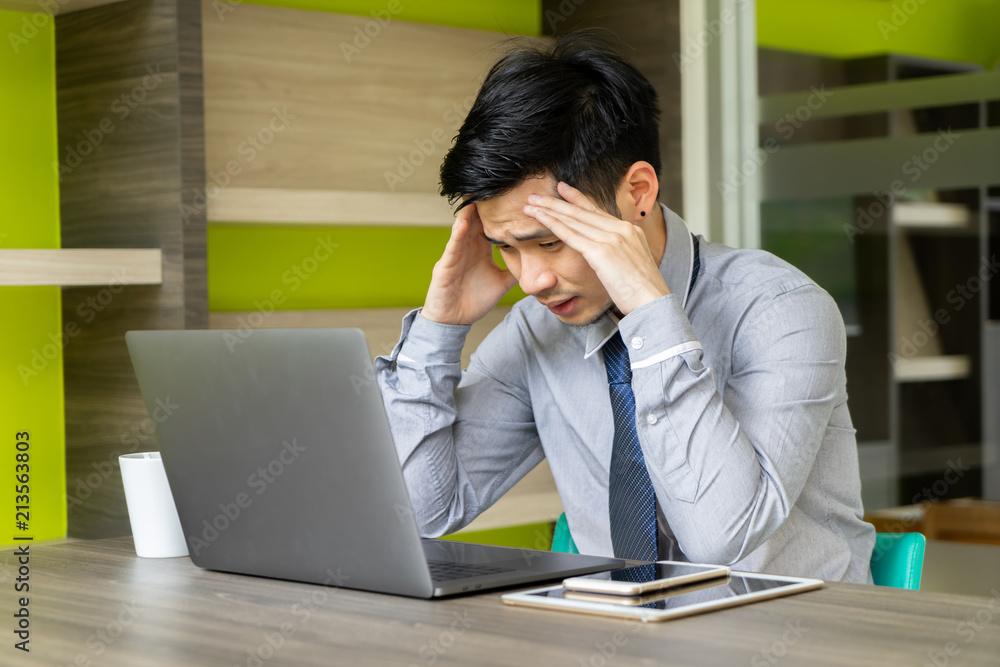 Business man feeling stressed with laptop computer. Young Asian male headache with project problem. people working with digital technology concept. Business man feeling stressed with laptop computer. Young Asian male headache with project problem. people working with digital technology concept.