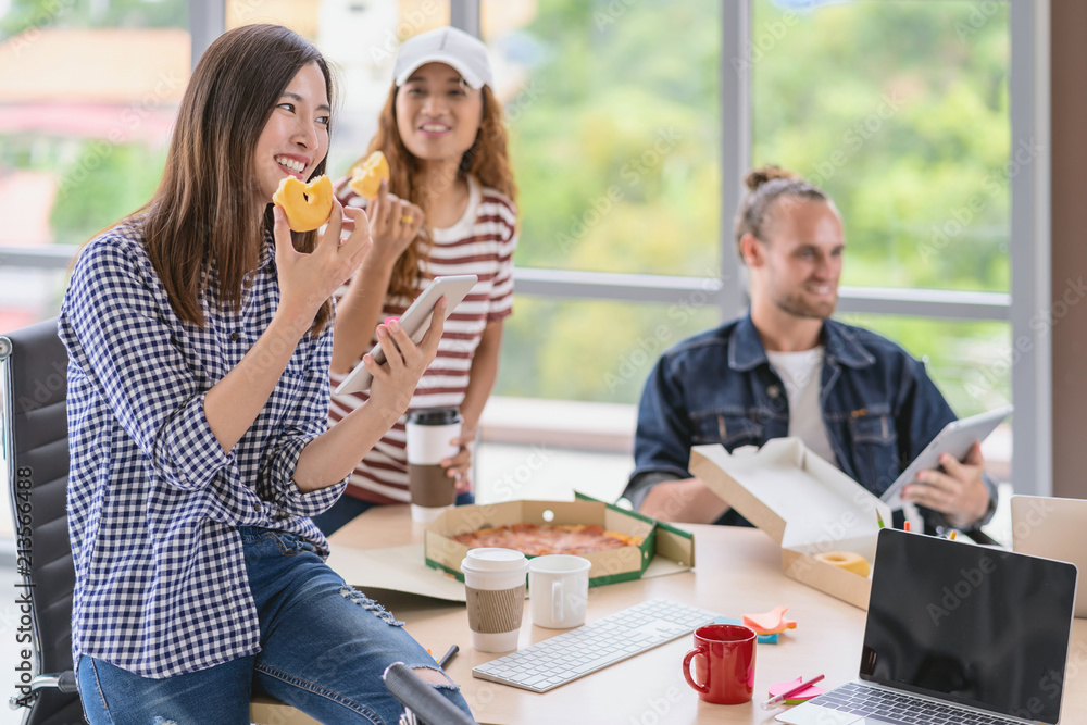 Asian worker with casual suit talking and eatting with happy action when lunch time in the creative office workplace, lifestyle and relax work concept
