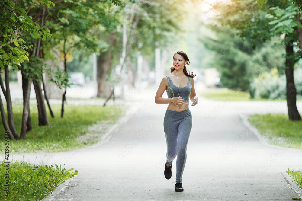 Young woman jogging down a path in a green park. Young woman jogging down a path in a green park.