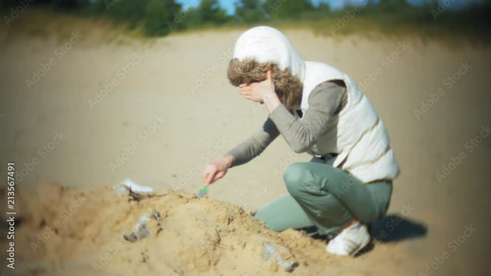 The woman is engaged in excavating bones in the sand, Skeleton and archaeological tools. The woman is engaged in excavating bones in the sand, Skeleton and archaeological tools.