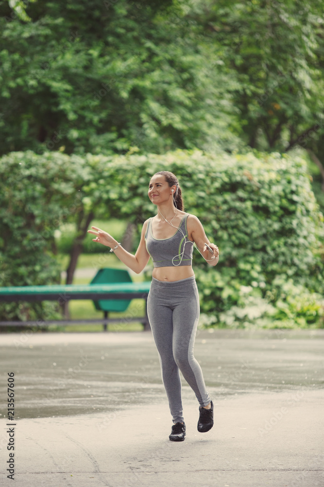 Young woman jogging down a path in a green park. Young woman jogging down a path in a green park.
