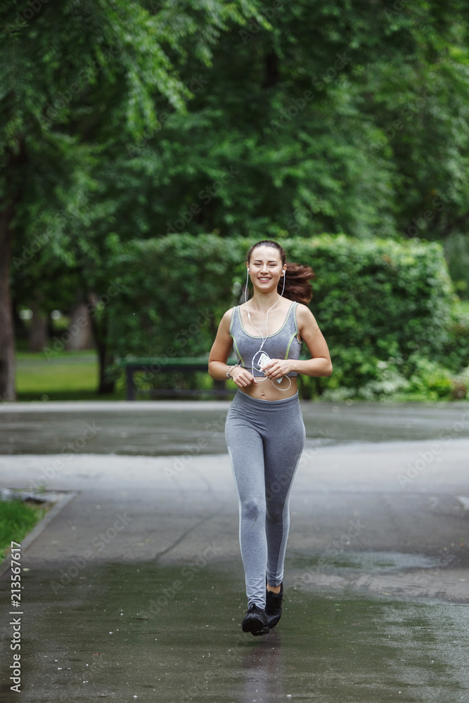 Young woman jogging down a path in a green park. Young woman jogging down a path in a green park.
