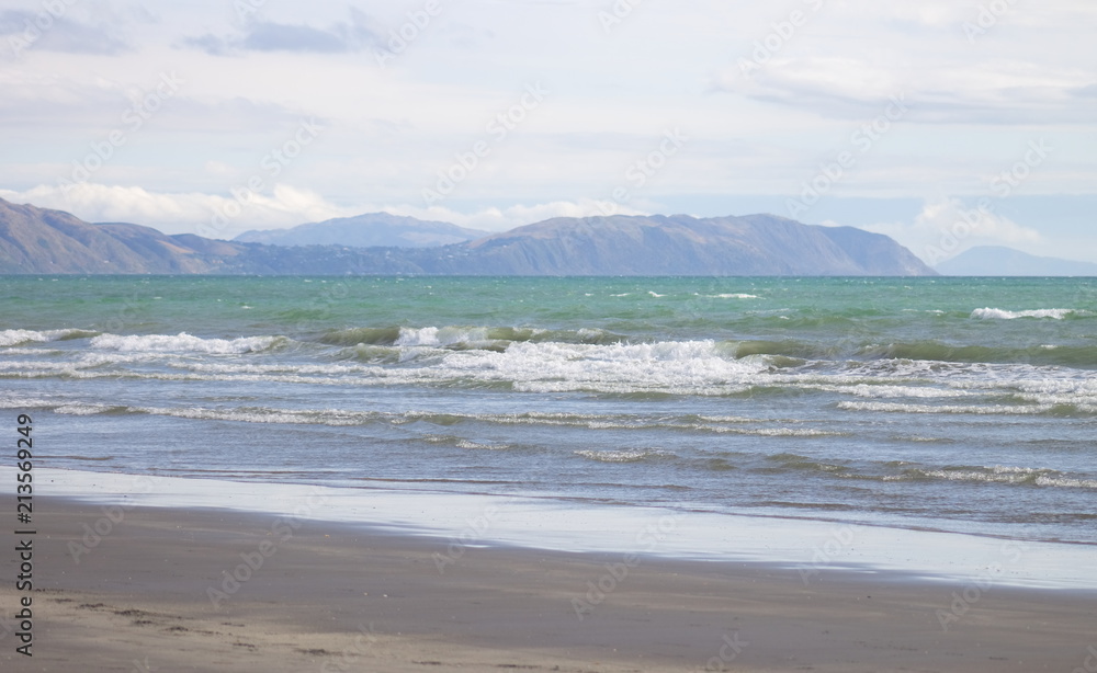 Waves coming in on Raumati Beach looking out towards Pukerua Bay and Porirua on the lower west coast of the North Island of New Zealand.