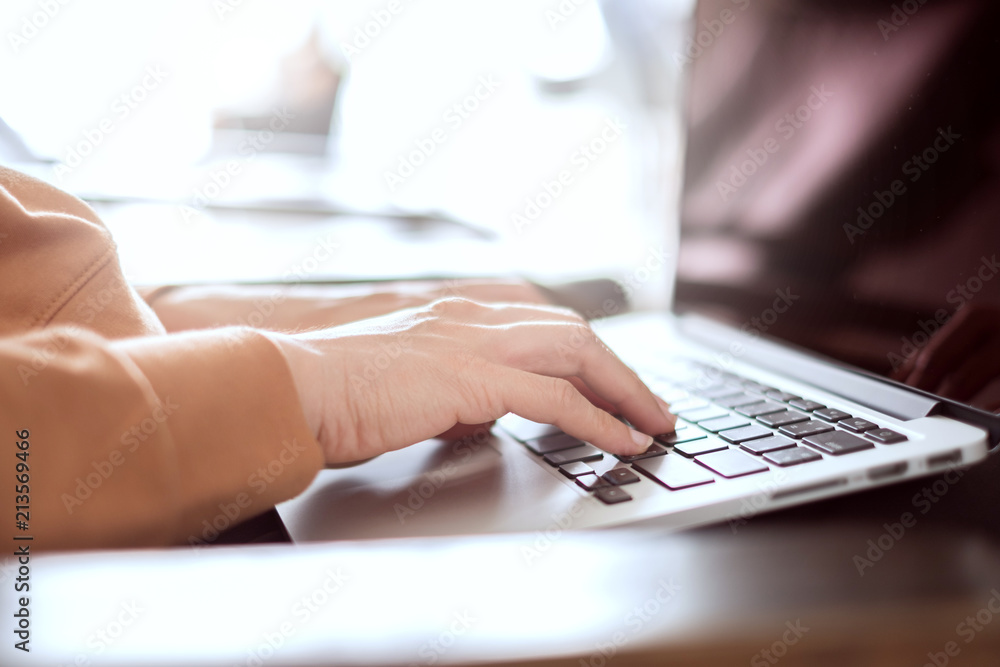 Closeup woman's hands typing on a laptop on a wooden desk - obrazy, fototapety, plakaty 