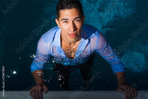 Handsome guy in swimming pool wearing shirt photo