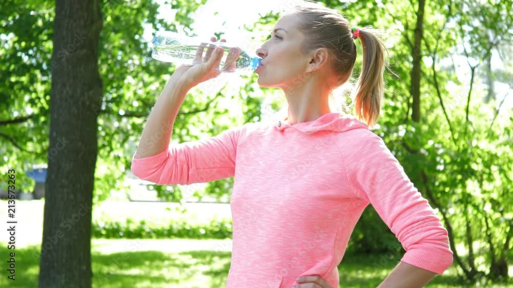 Fitness woman running in summer park. Drink water from bottle Fitness woman running in summer park. Drink water from bottle