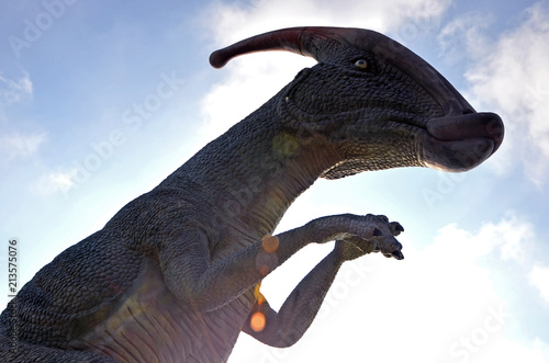 Dinosaur Parasaurolophus against a blue sky with clouds