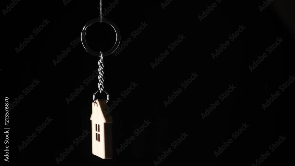 Wooden key holder with house shape hanging and rotating on black background Wooden key holder with house shape hanging and rotating on black background