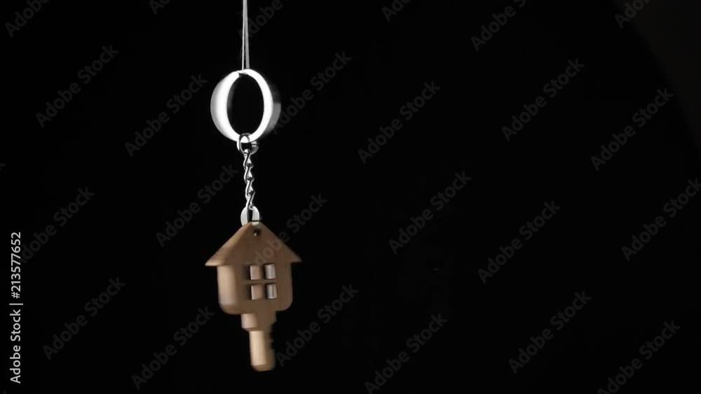 Wooden key holder with house shape hanging and rotating on black background Wooden key holder with house shape hanging and rotating on black background
