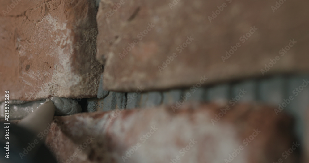 Slow motion closeup of worker filling seam between bricks with mortar from sealant gun Slow motion closeup of worker filling seam between bricks with mortar from sealant gun