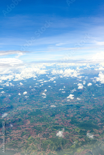 Beautiful view of blue sky above the white clouds and land background from airplane window