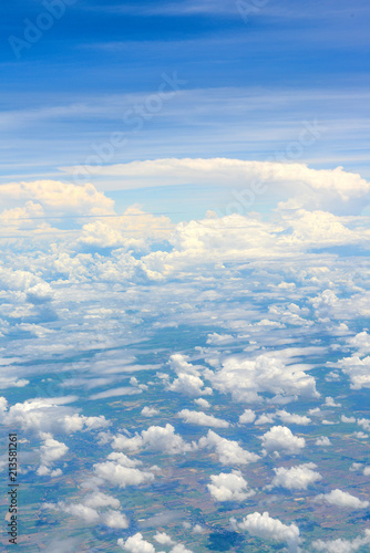 Beautiful view of blue sky above the white clouds and land background from airplane window